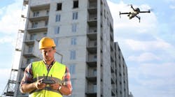 Builder operating drone with remote control at construction site. Aerial photography