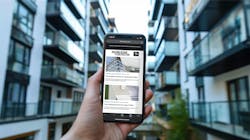 Hand holding smartphone in front of modern apartment building Hand holding smartphone in front of modern apartment building