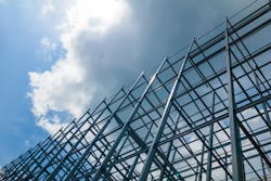 A large building of steel structure in the sky with sun and clouds.