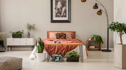 king size bed with rust color bedding in spacious bedroom interior of modern apartment, real photo