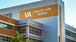 Veterans Administration Health Care Center. Horizontal, medium closeup of VA Health Care Center medical facilities exterior facade brand and logo signage adorning the modern architecture of the building in Charlotte, North Carolina with floors of reflective windows and a clear blue sky in the soft light of early morning.